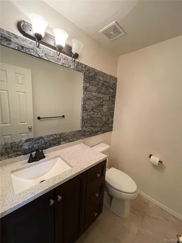 a bathroom with a granite countertop sink a toilet and mirror