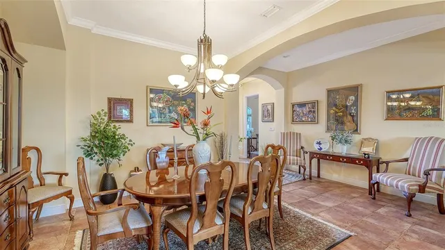 a view of a dining room with furniture a chandelier and large windows
