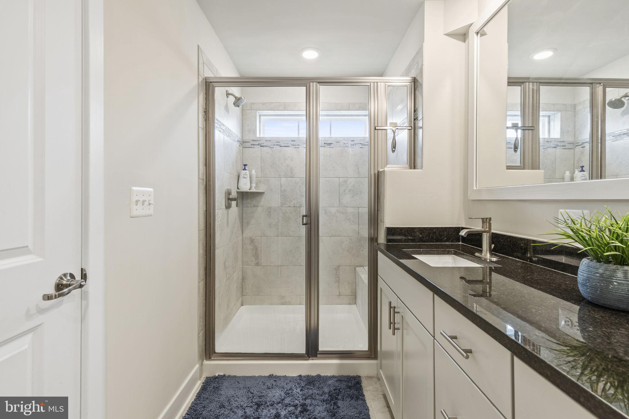2045 Ivory Brook Road Baltimore, MD 21244 - Photo 20 of 39 a bathroom with a granite countertop sink a mirror a glass door a shower and vanity