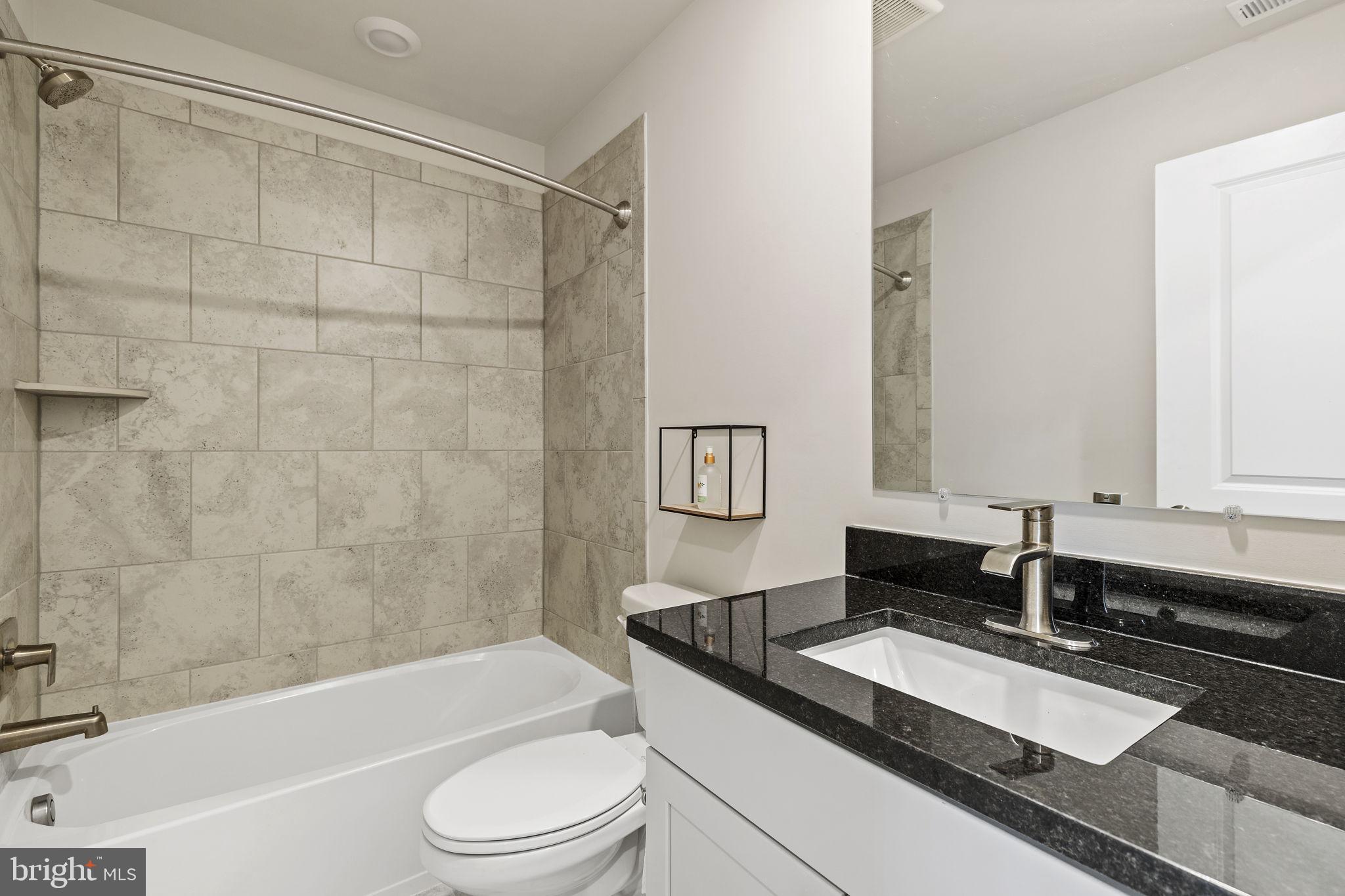 2045 Ivory Brook Road Baltimore, MD 21244 - Photo 26 of 39 a bathroom with a granite countertop sink a toilet a mirror a bathtub and shower