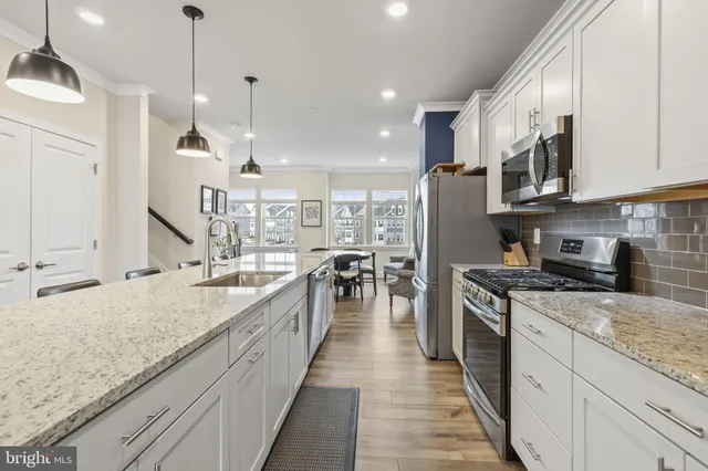 a large kitchen with stainless steel appliances granite countertop a stove oven and a white cabinets