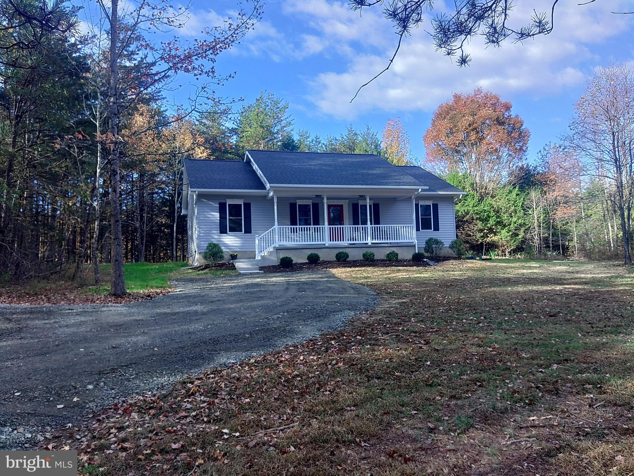 a front view of a house with a yard and large trees