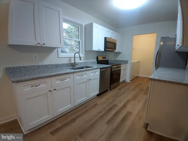 a kitchen with a sink cabinets appliances and a window