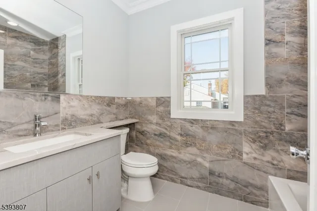 a bathroom with a granite countertop toilet a sink and a window