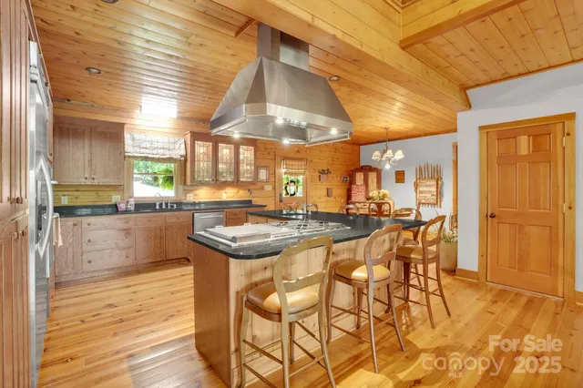 a kitchen with stainless steel appliances kitchen island granite countertop a table chairs sink and cabinets