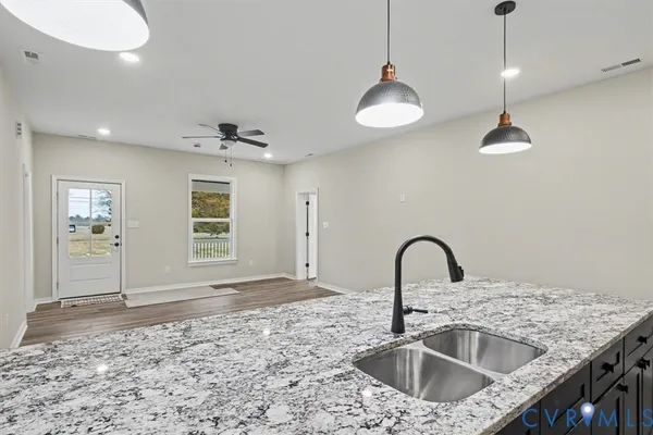 a kitchen with a sink a counter top space and a view of living room