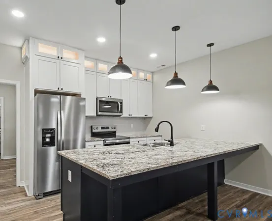 a kitchen with granite countertop stainless steel appliances a sink cabinets a refrigerator and a counter top
