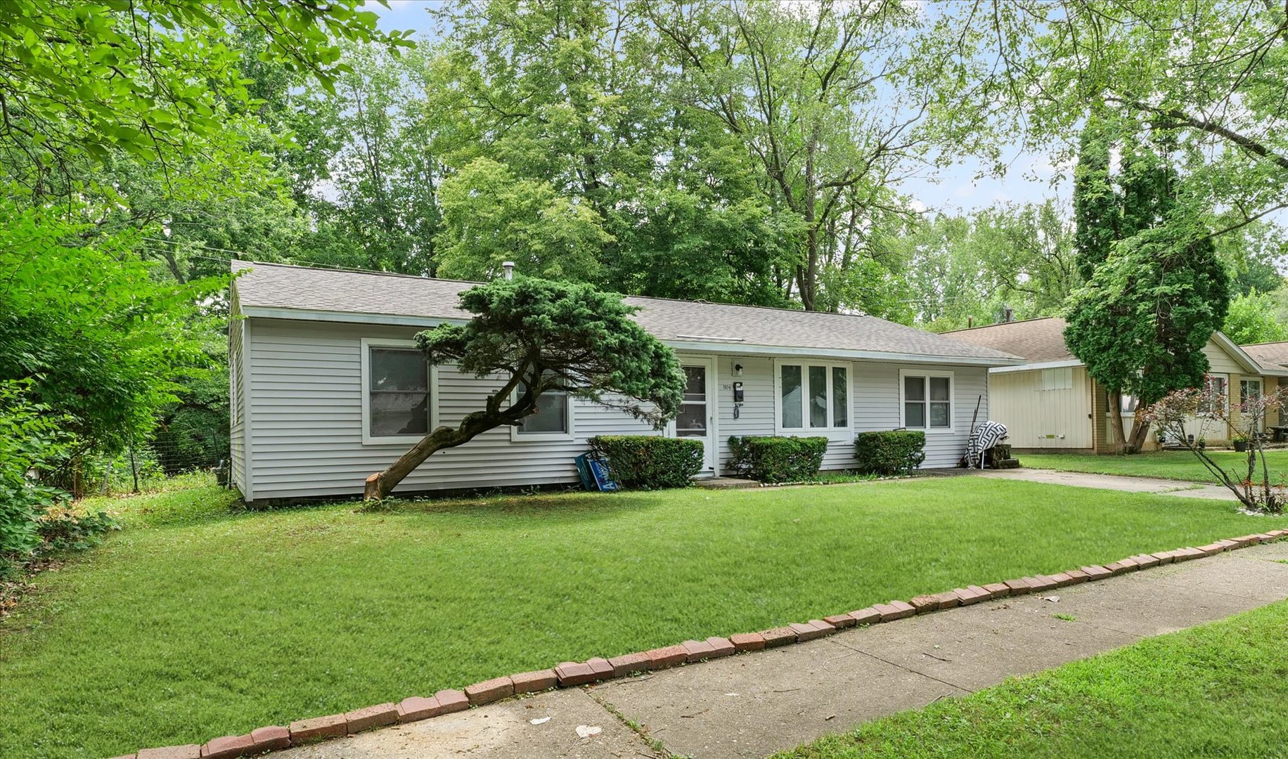 1104 Lanore Drive Urbana, IL 61802 - Photo 3 of 16 a front view of a house with a garden and trees