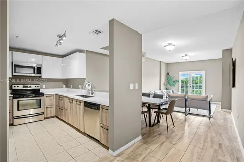 a kitchen with stainless steel appliances granite countertop a stove top oven a sink dishwasher and white cabinets with wooden floor