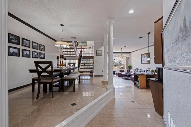 a view of a dining room and livingroom with furniture wooden floor a rug a flat screen tv a painting and a chandelier