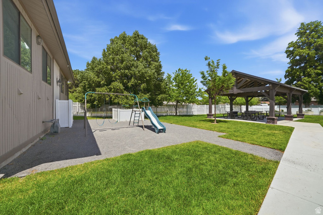 6969 South 855 East Midvale, UT 84047 - Photo 53 of 55 Expansive outdoor amenity area featuring a covered pavilion with picnic tables, a dedicated children's play structure, manicured green space, and a white picket fence perimeter