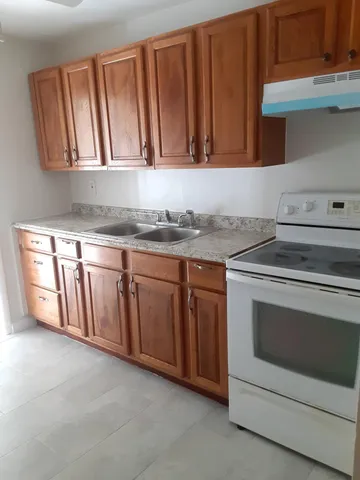 a large kitchen with granite countertop a stove a sink and a microwave