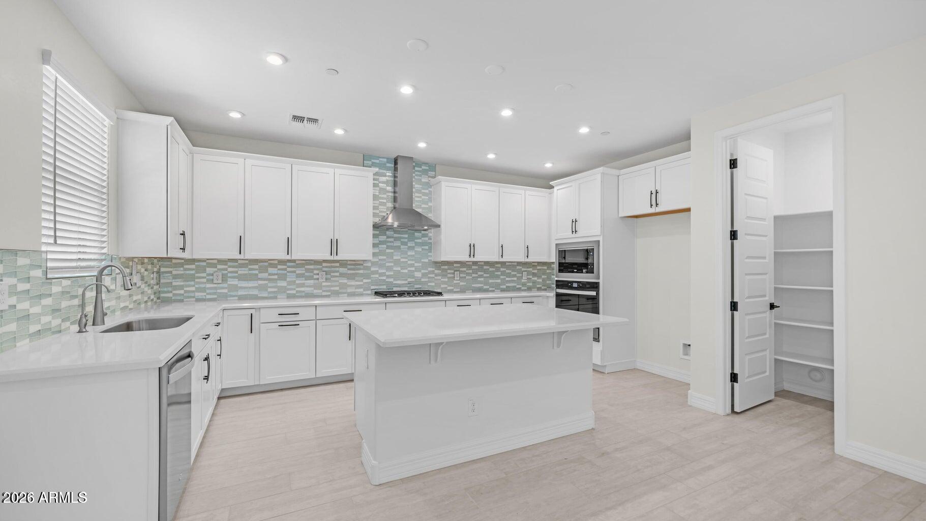 a kitchen with kitchen island a sink stainless steel appliances and cabinets