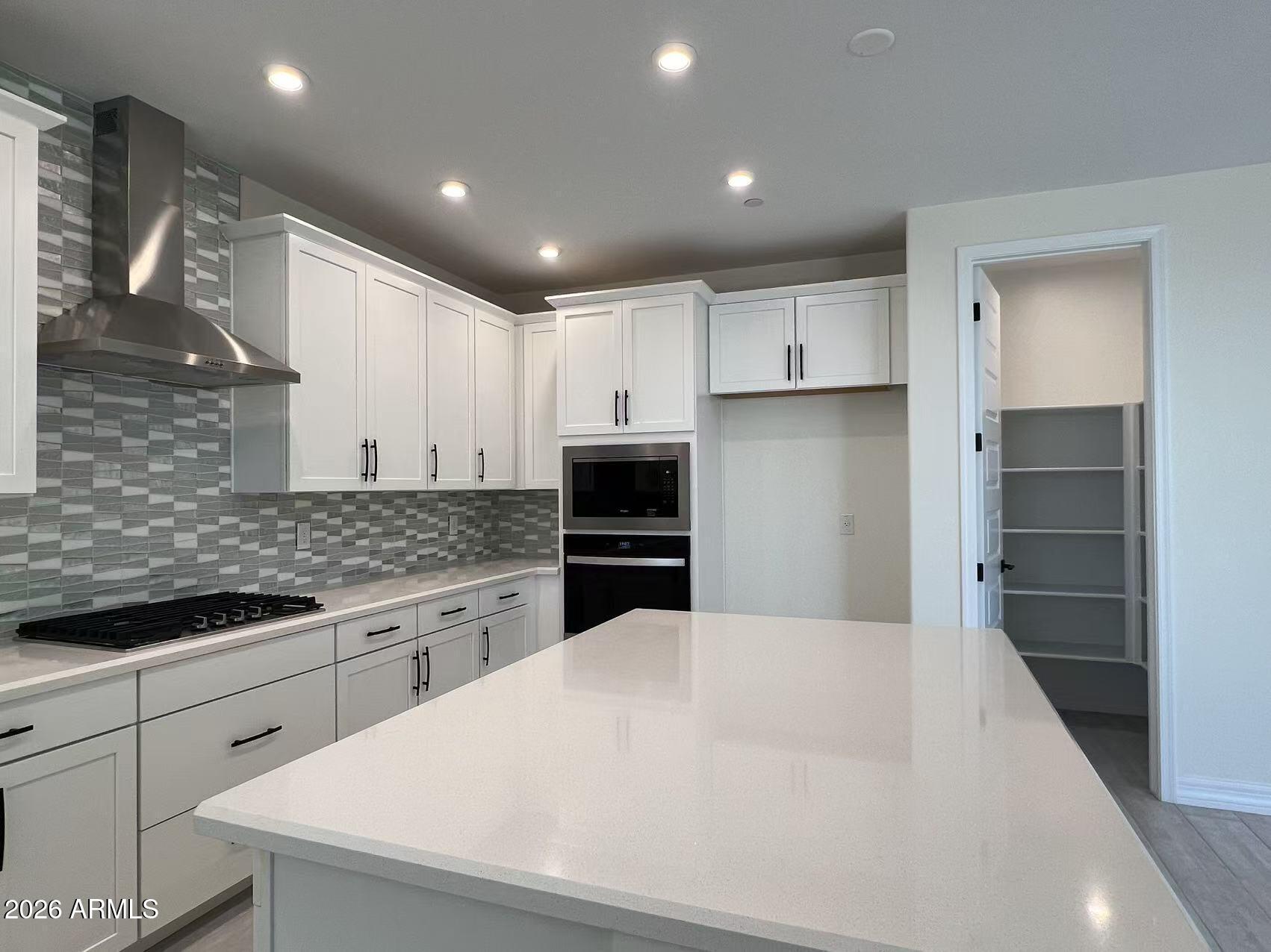 13359 West Eagle Feather Road Peoria, AZ 85383 - Photo 12 of 43 a kitchen with white cabinets and stainless steel appliances