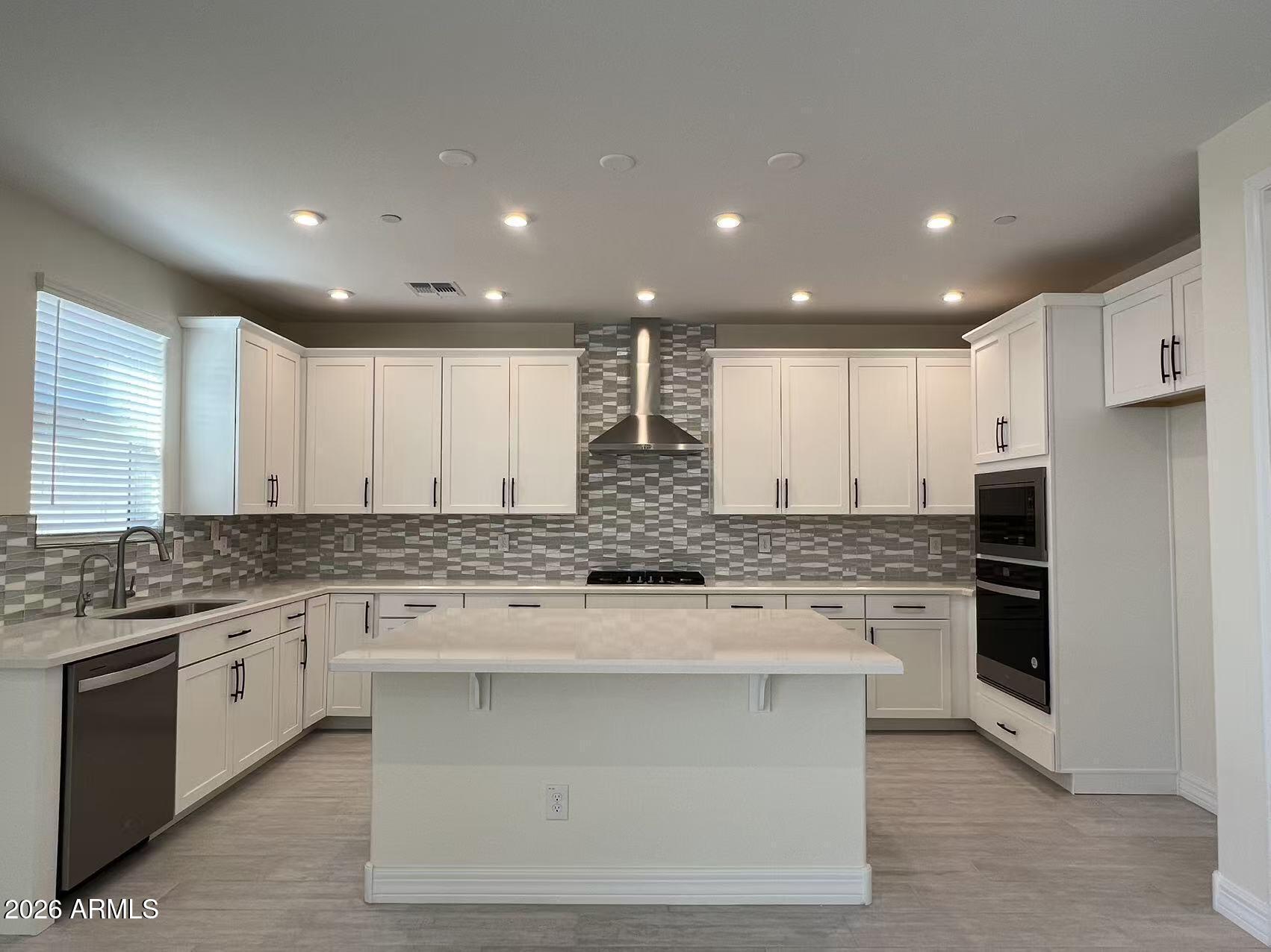 13359 West Eagle Feather Road Peoria, AZ 85383 - Photo 17 of 43 a large kitchen with stainless steel appliances kitchen island granite countertop a stove and a sink