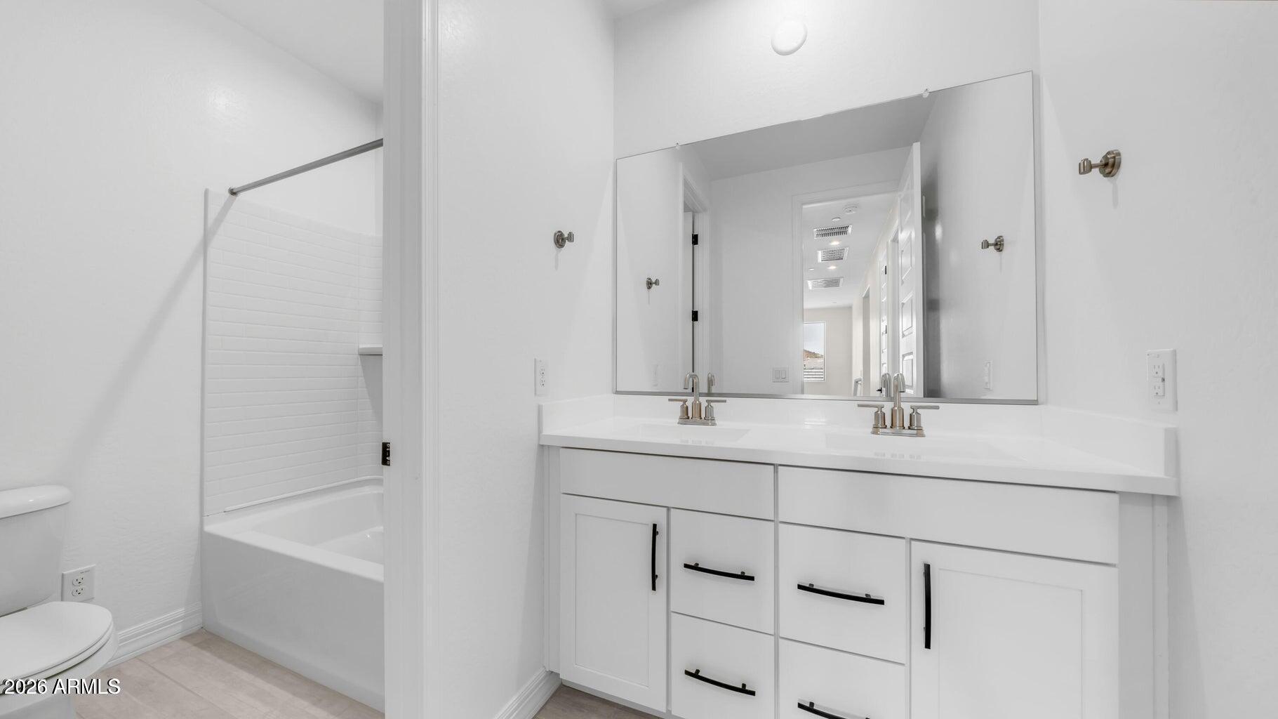 13359 West Eagle Feather Road Peoria, AZ 85383 - Photo 25 of 43 a bathroom with a double vanity sink toilet mirror and bathtub