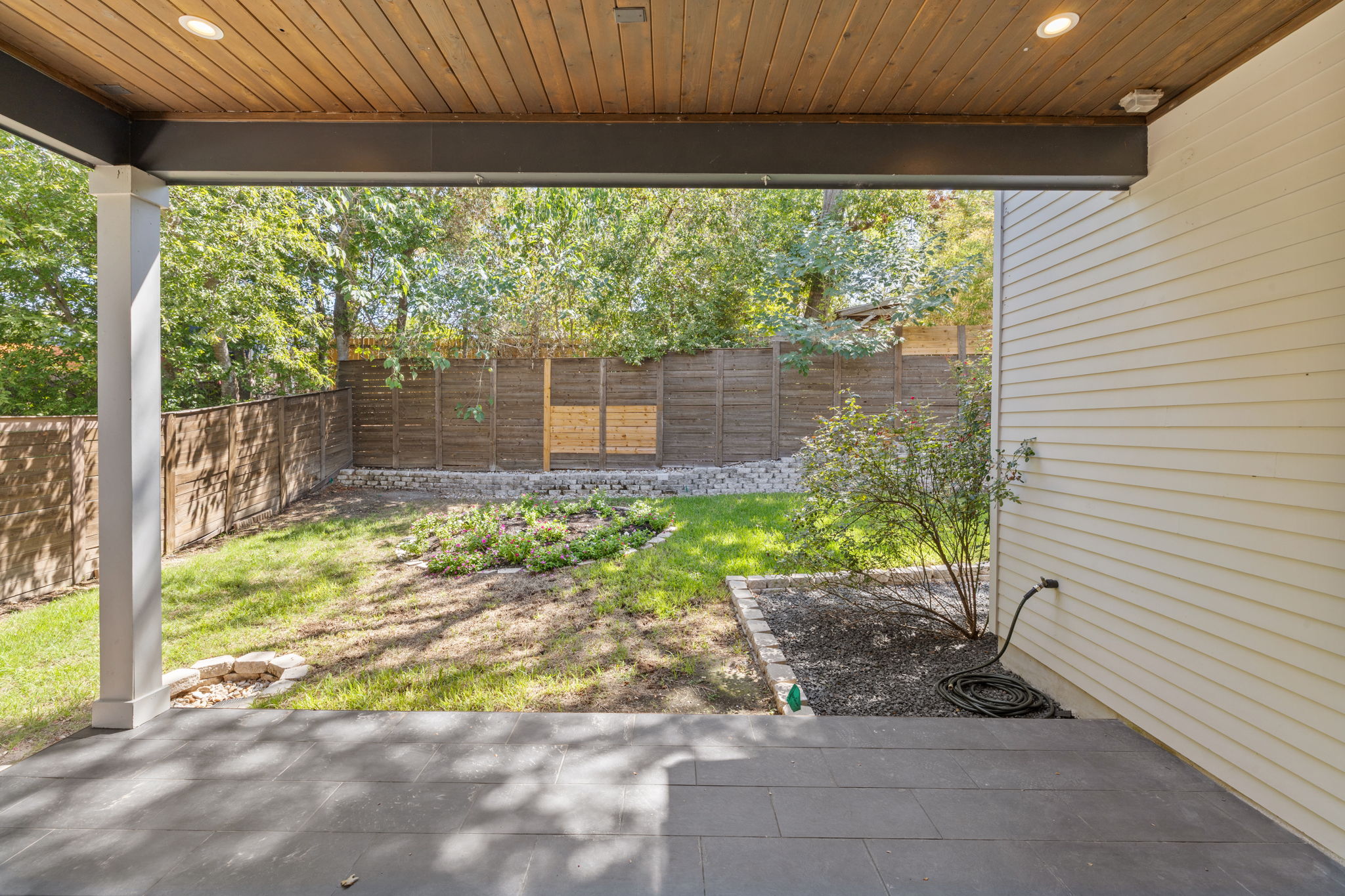 1719 Bunche Road Austin, TX 78721 - Photo 30 of 36 A covered stone patio opens directly to a fenced backyard shaded by mature trees.