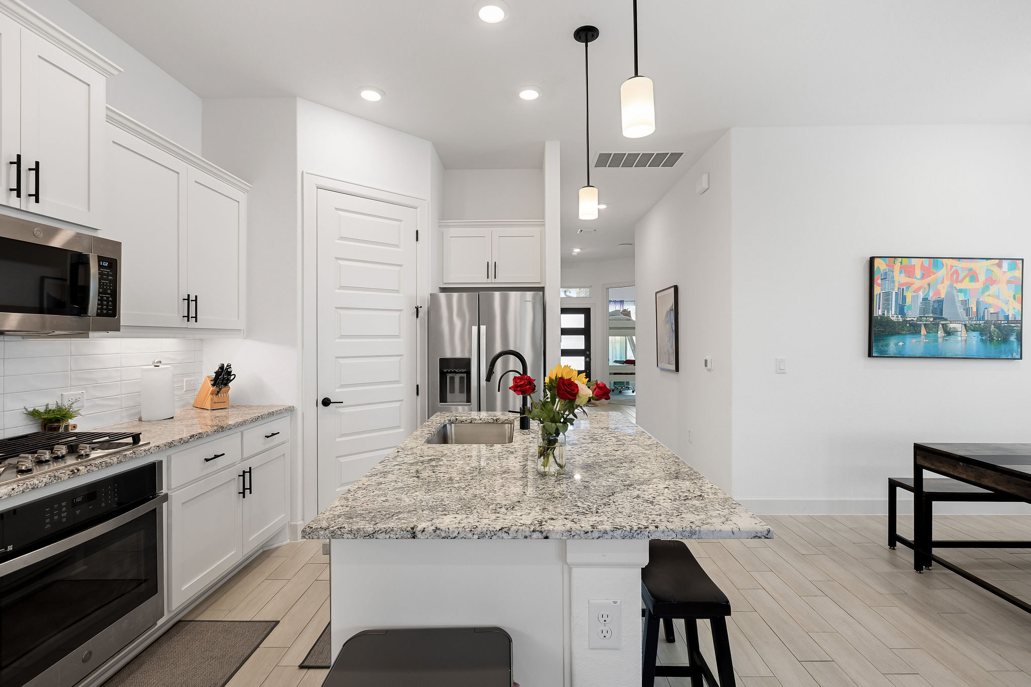 4605 Sea Salt Drive Austin, TX 78747 - Photo 9 of 40 a kitchen with kitchen island granite countertop a stove a sink a dining table and chairs with wooden floor