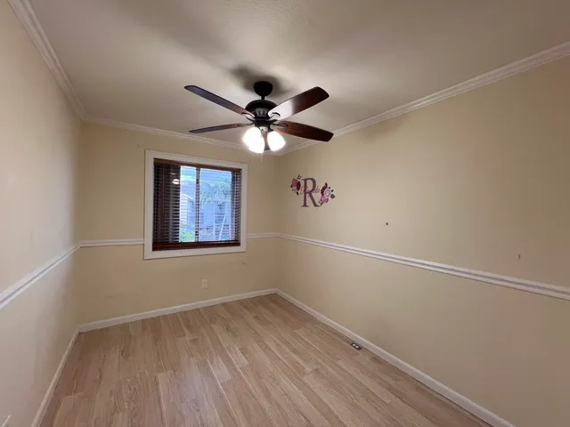 an empty room with a hardwood and ceiling fan