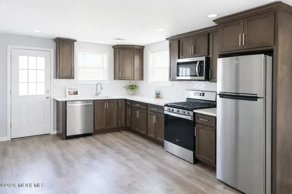 a kitchen with stainless steel appliances granite countertop a sink a stove a refrigerator cabinets and wooden floor
