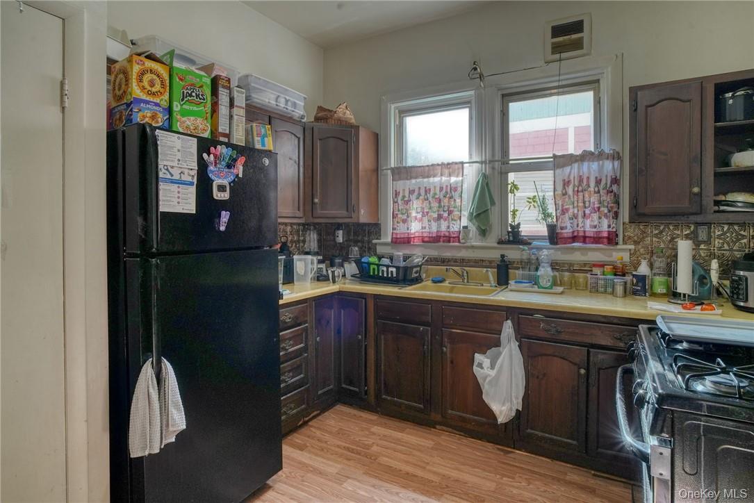 32 Balding Avenue Poughkeepsie, NY 12601 - Photo 11 of 39 Kitchen featuring sink, black appliances, dark brown cabinets, and light wood-type flooring