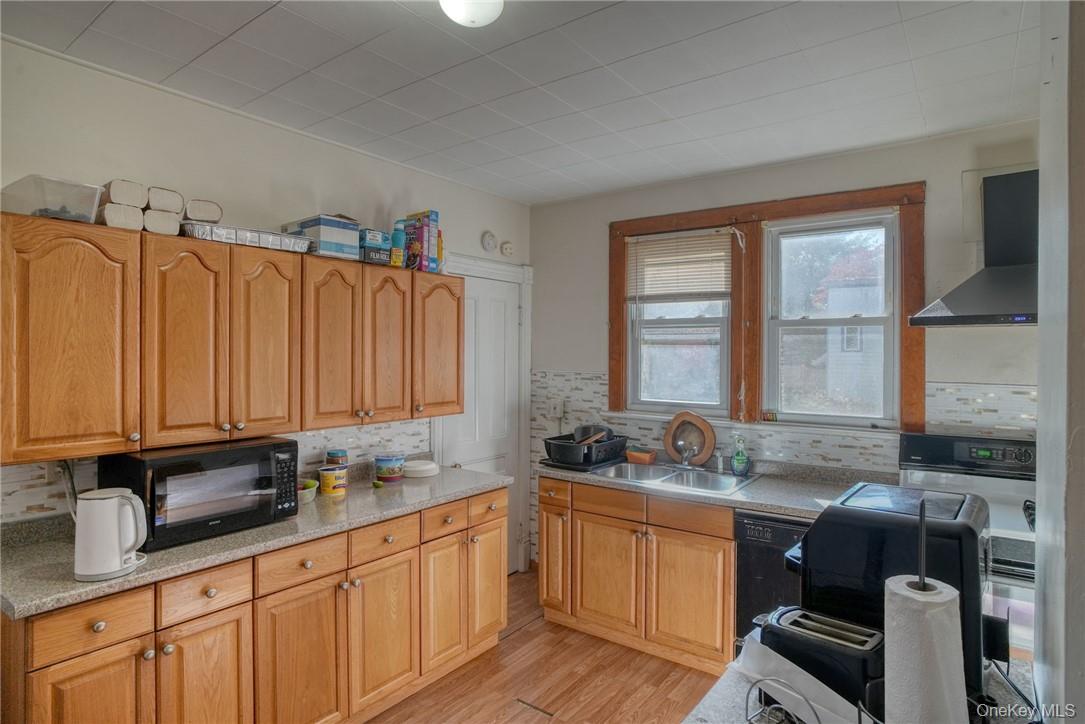 32 Balding Avenue Poughkeepsie, NY 12601 - Photo 19 of 39 Kitchen with light hardwood / wood-style flooring, black appliances, backsplash, and range hood