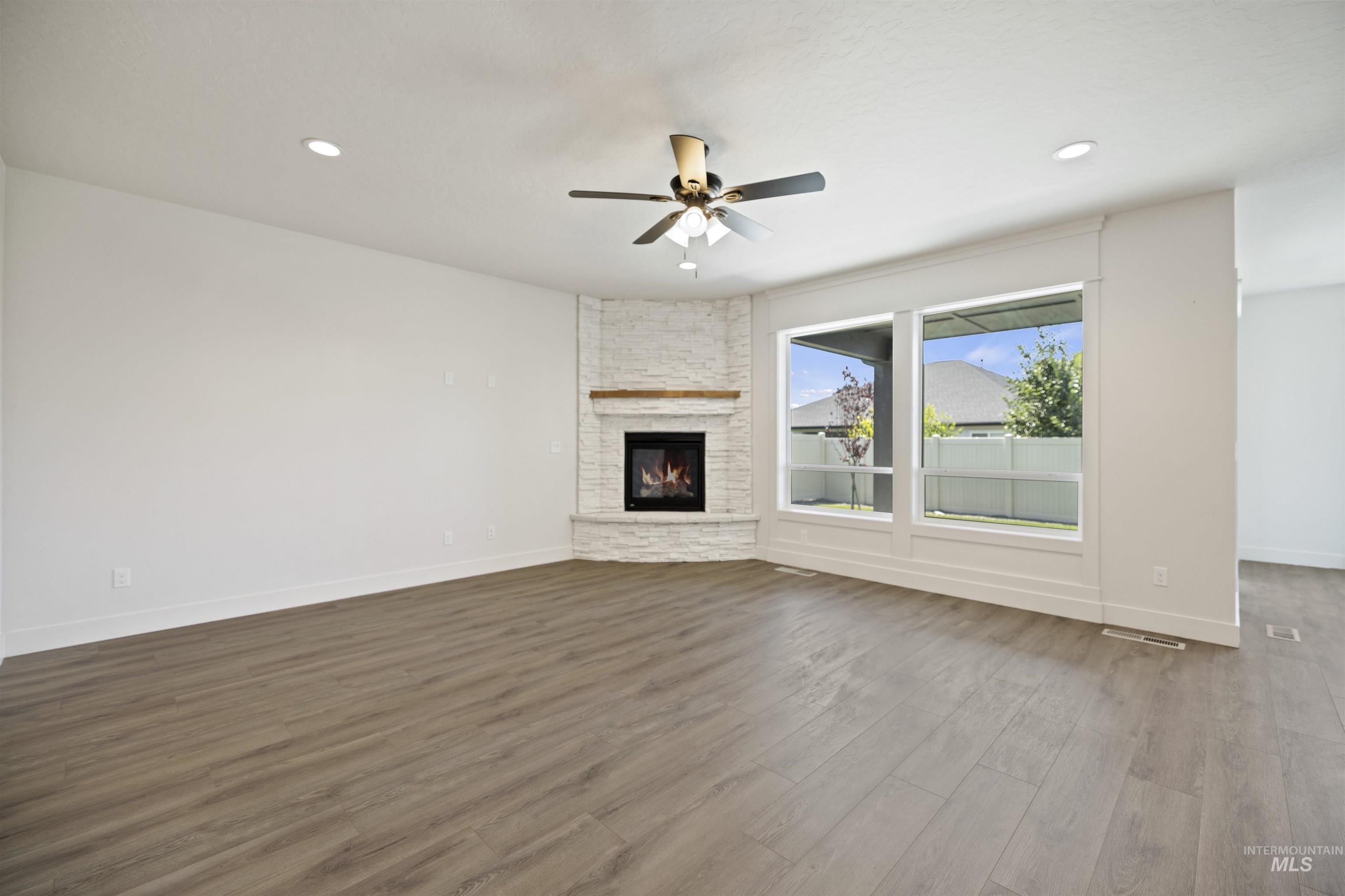 3515 South El Rio Avenue Boise, ID 83709 - Photo 9 of 47 Unfurnished living room with ceiling fan, dark wood-style floors, a fireplace, and recessed lighting