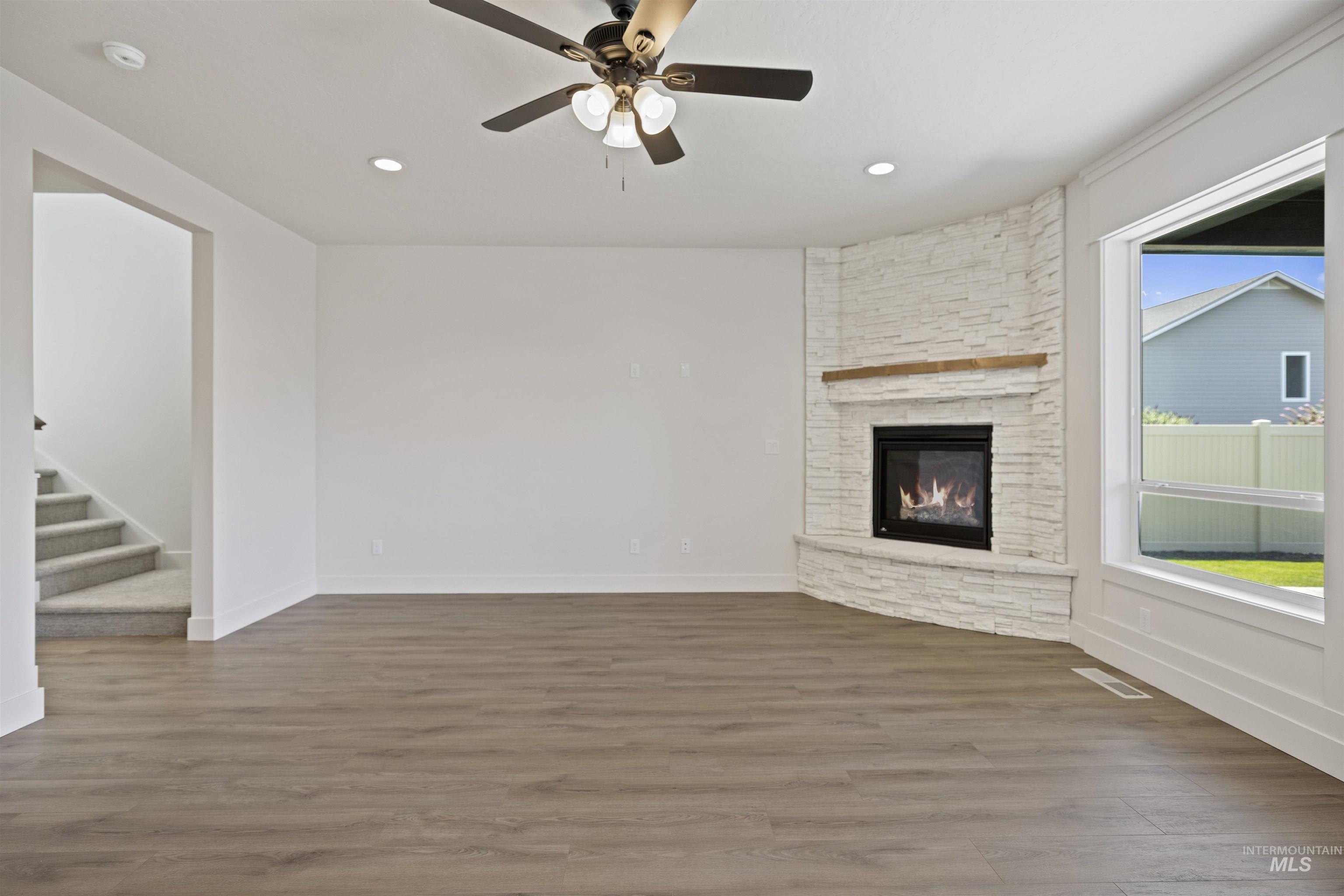 3515 South El Rio Avenue Boise, ID 83709 - Photo 10 of 47 Unfurnished living room featuring wood finished floors, a fireplace, stairs, ceiling fan, and recessed lighting