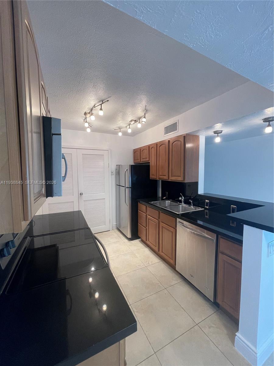 7483 Southwest 82nd Street, Unit A101 Miami, FL 33143 - Photo 11 of 39 a large kitchen with granite countertop a large stove top oven and cabinets
