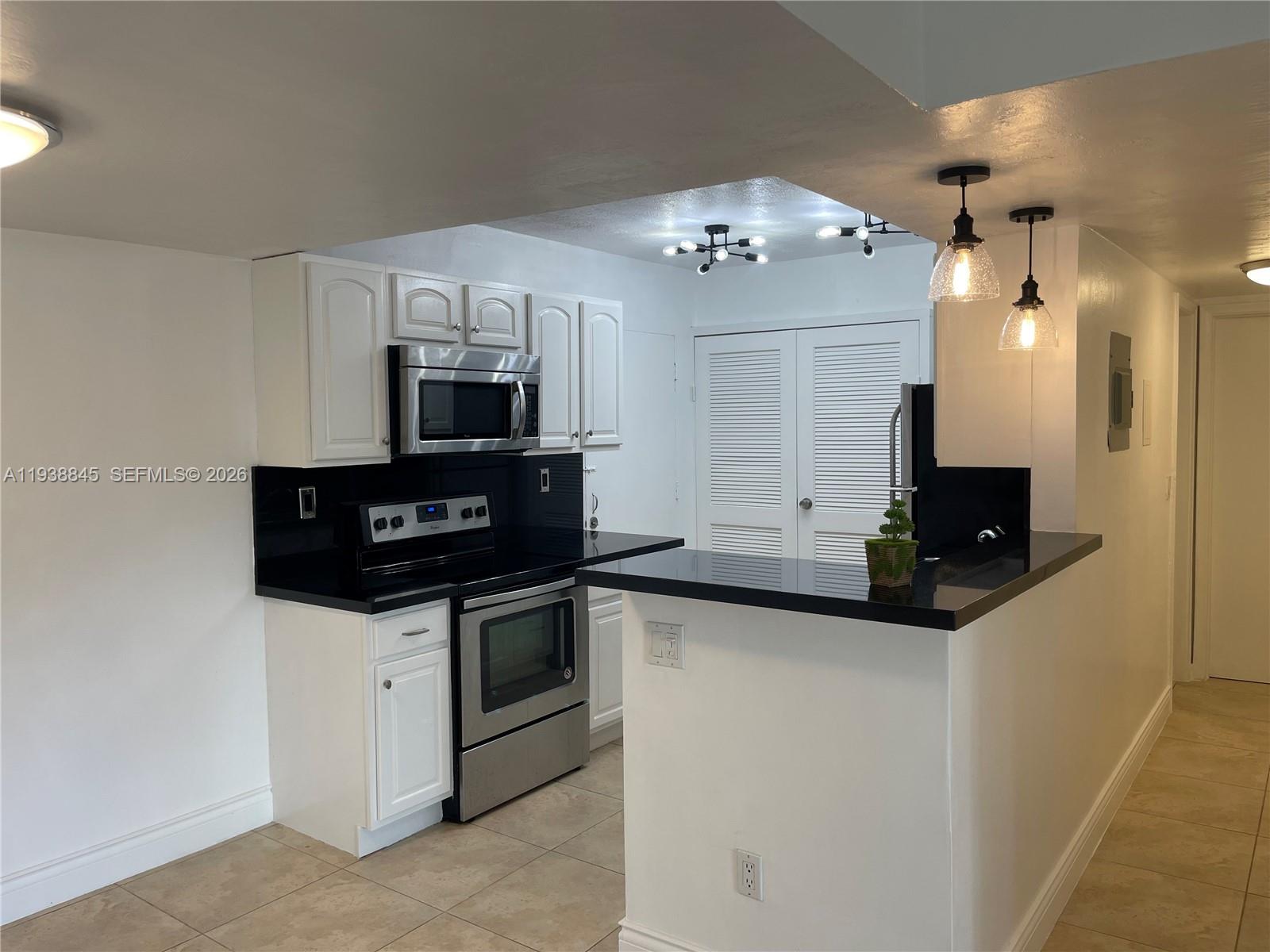 7483 Southwest 82nd Street, Unit A101 Miami, FL 33143 - Photo 13 of 39 a kitchen with granite countertop a sink and a stove top oven with wooden floor