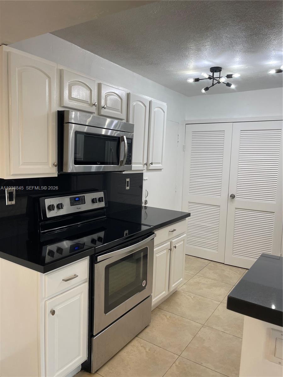 7483 Southwest 82nd Street, Unit A101 Miami, FL 33143 - Photo 14 of 39 a kitchen with granite countertop a stove and a sink