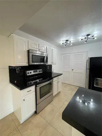 a kitchen with stainless steel appliances a stove a microwave a sink and cabinets