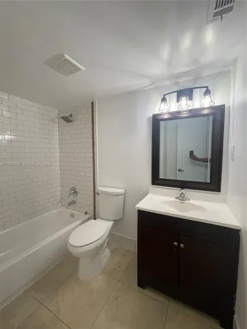a bathroom with a toilet sink mirror vanity and bathtub