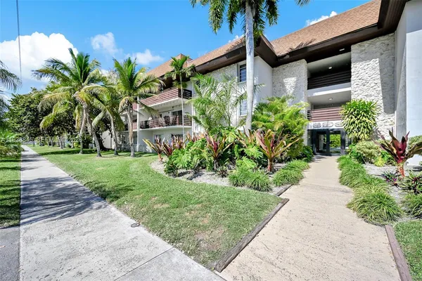 a front view of yellow house with a yard and potted plants