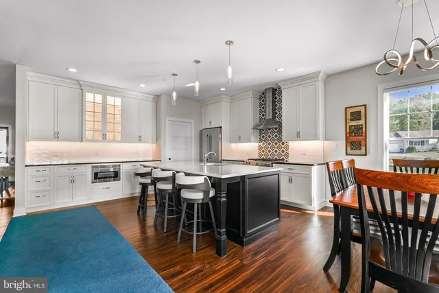 a dining hall with stainless steel appliances granite countertop a dining table chairs and a large window