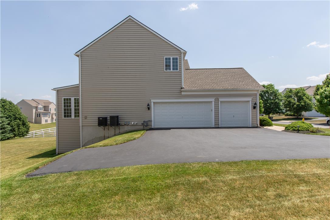 1709 Travers Road Breinigsville, PA 18031 - Photo 51 of 55 A well-maintained side exterior presents multiple garage doors and a paved driveway leading to a manicured lawn.