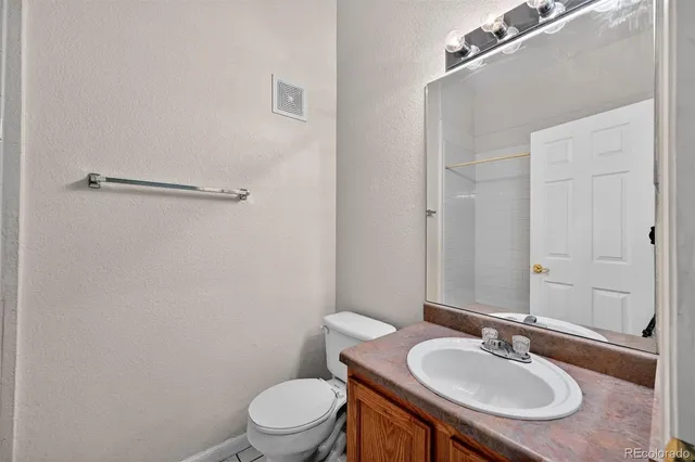 a bathroom with a granite countertop sink a toilet a mirror and shower