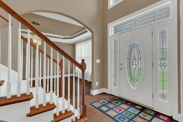 a view of a hallway with wooden floor stairs and a chandelier