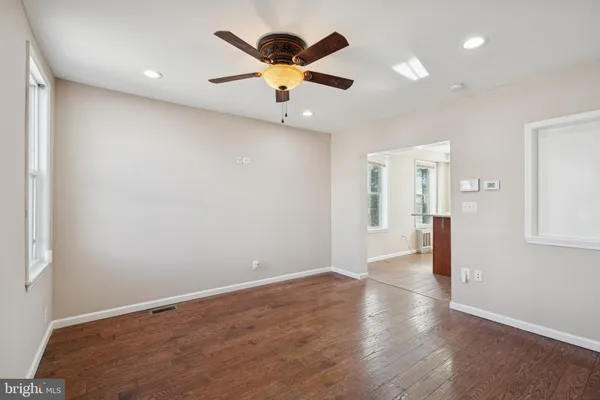 an empty room with wooden floor and windows
