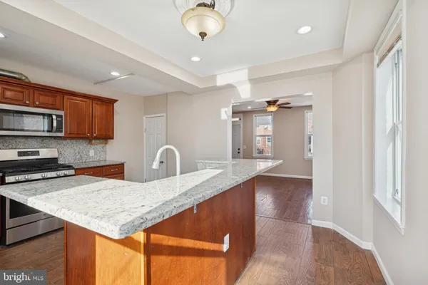 a kitchen with stainless steel appliances granite countertop a sink dishwasher and a stove with wooden floor