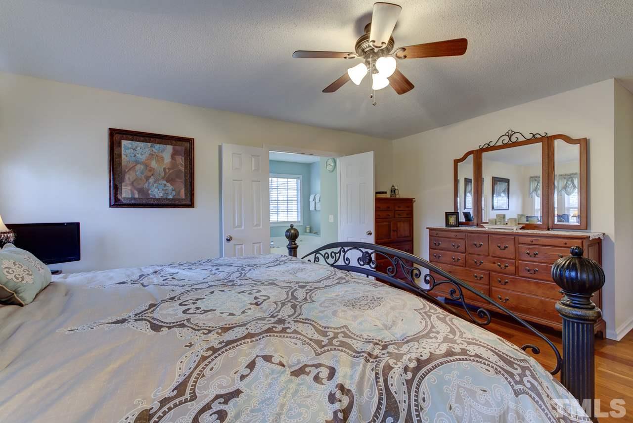 247 Cross Ridge Drive Willow Spring, NC 27592 - Photo 14 of 25 a bedroom with a large bed and a chandelier
