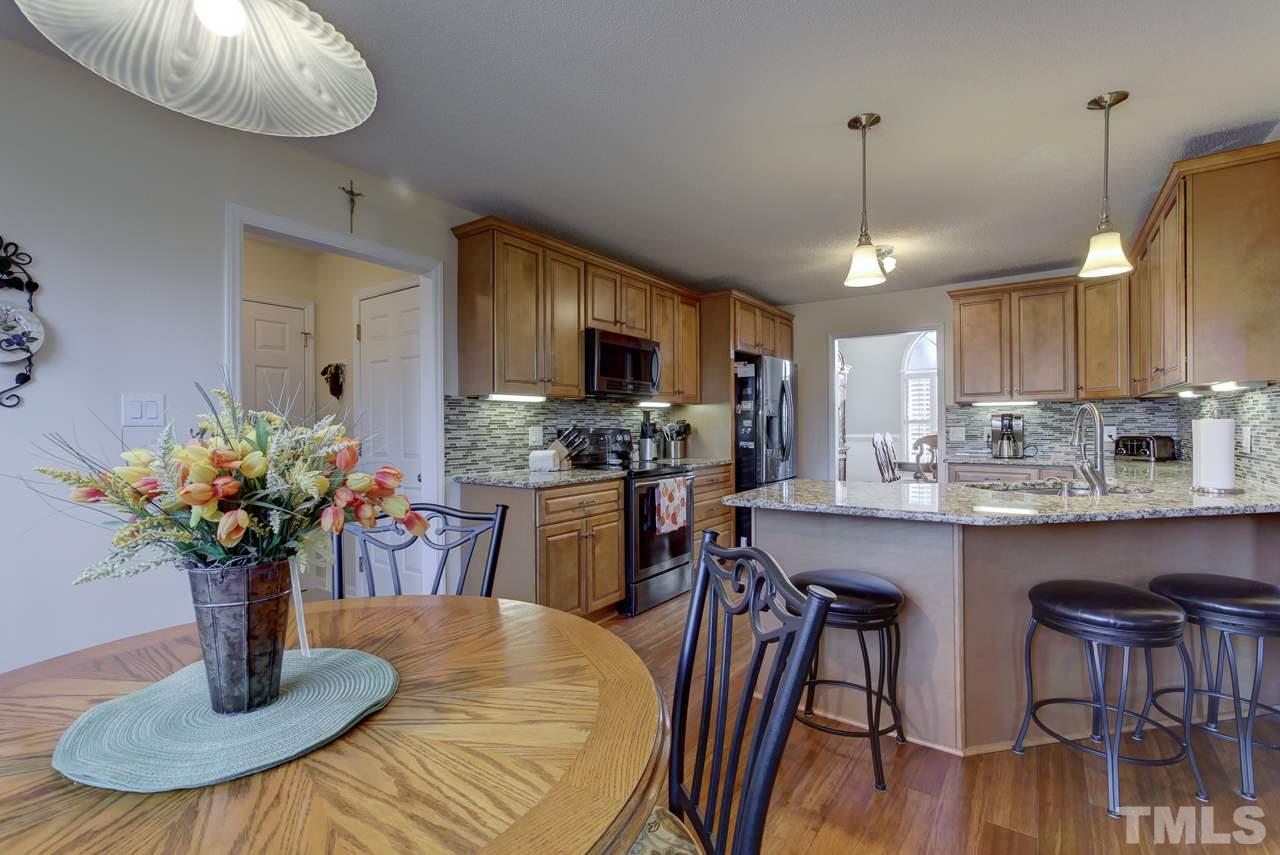 247 Cross Ridge Drive Willow Spring, NC 27592 - Photo 7 of 25 a kitchen with granite countertop a table chairs a sink and cabinets