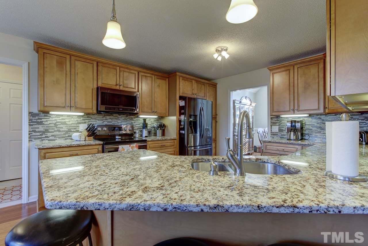 247 Cross Ridge Drive Willow Spring, NC 27592 - Photo 8 of 25 a kitchen with kitchen island granite countertop a sink stove and refrigerator