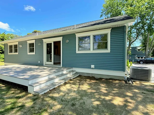 a view of house with backyard and trees in the background