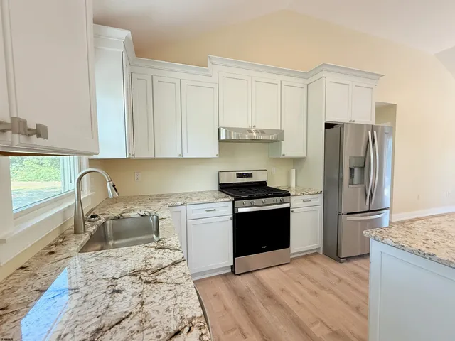 a kitchen with granite countertop a refrigerator stove top oven and sink