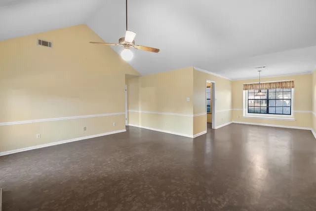 an empty room with windows and ceiling fan