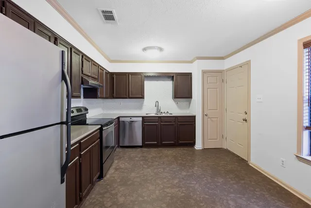 a kitchen with granite countertop a refrigerator and a stove top oven