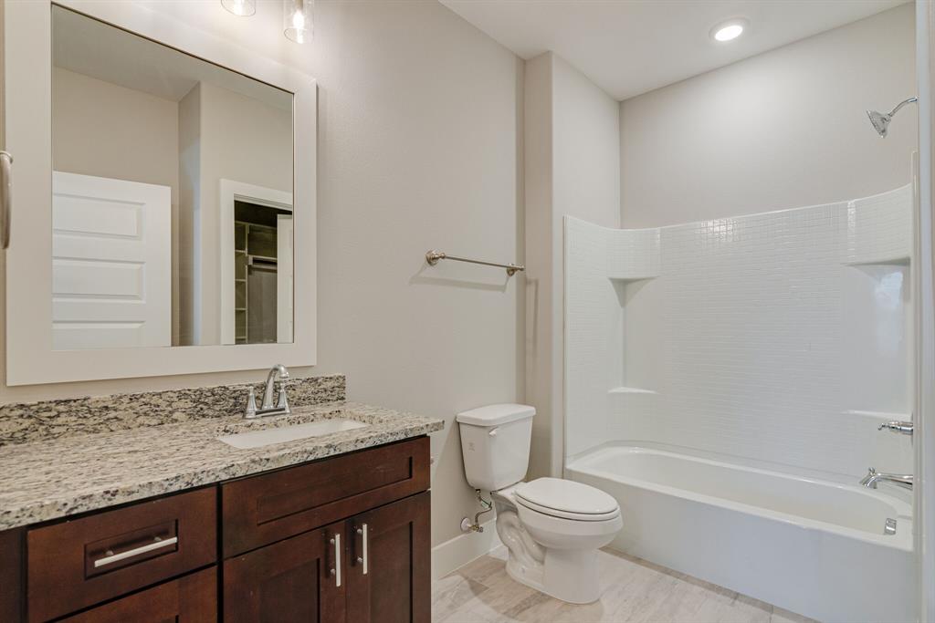 115 West Jones Street, Unit 201 Krum, TX 76249 - Photo 14 of 15 a bathroom with a granite countertop sink toilet and shower