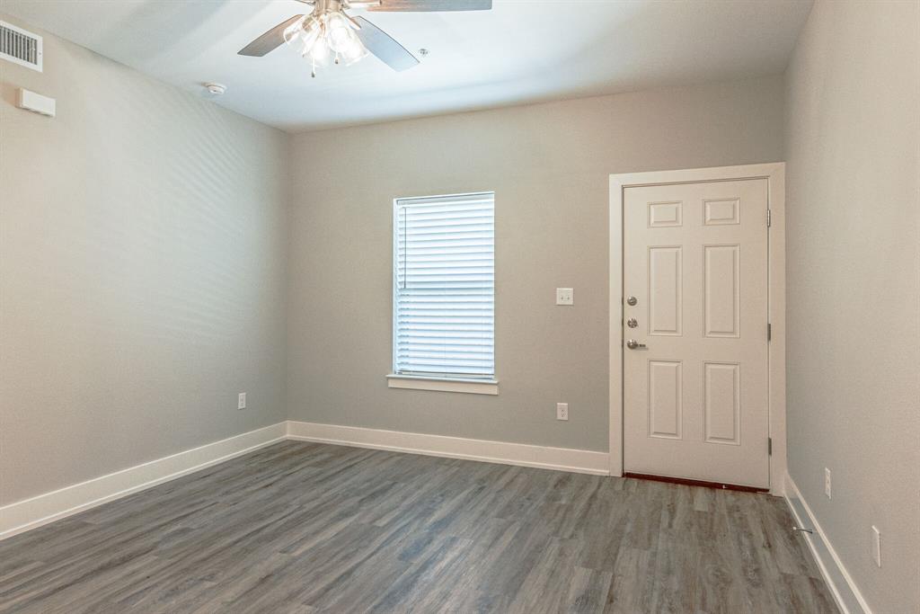 115 West Jones Street, Unit 201 Krum, TX 76249 - Photo 3 of 15 an empty room with wooden floor and windows