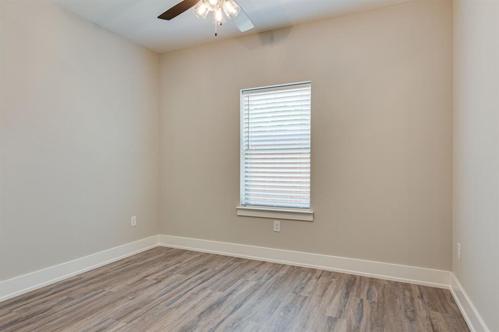115 West Jones Street, Unit 201 Krum, TX 76249 - Photo 8 of 15 an empty room with wooden floor and windows